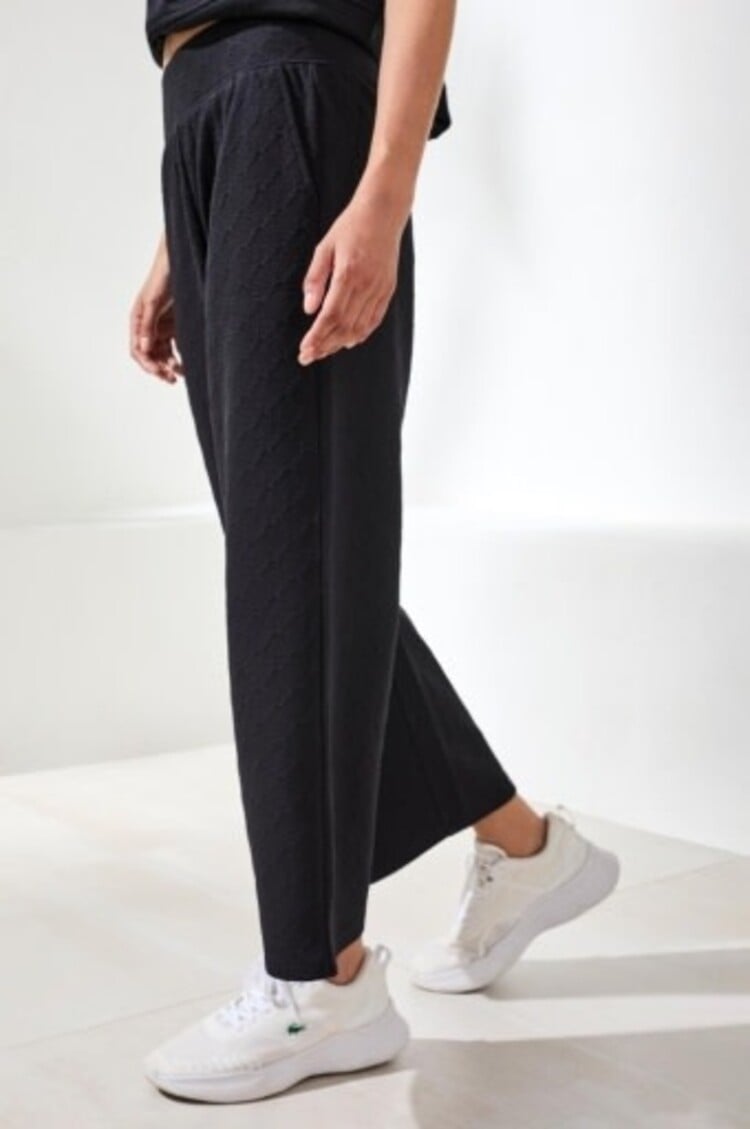 Woman wearing black pull-on capri pants with pockets and white sneakers
