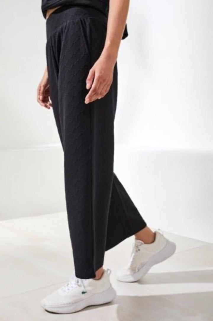 Woman wearing black pull-on capri pants with pockets and white sneakers