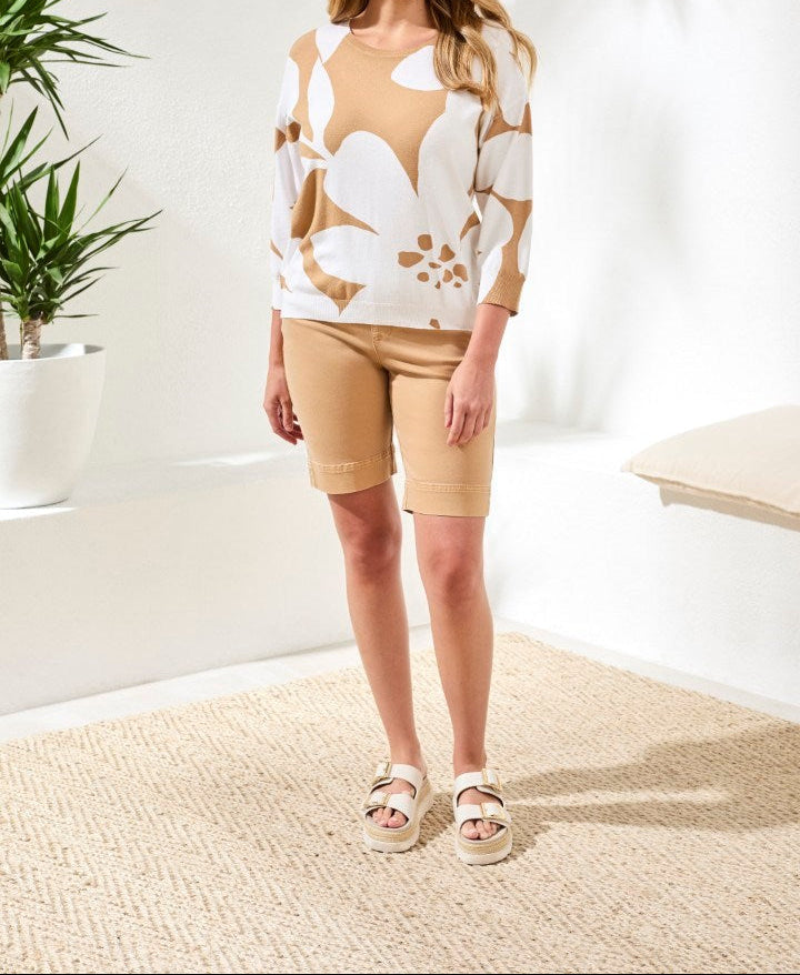 Woman wearing beige 3/4 sleeve crew neck sweater with white floral print and matching shorts