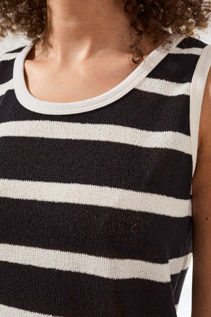 Woman wearing black and white striped sleeveless knit top with ribbed neckline