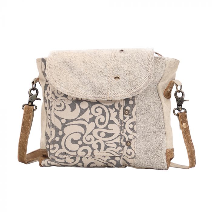 Messenger bag with canvas and hairon leather combo, side hairon accents, and secure top closure—rugged-chic for bold women 30+.









